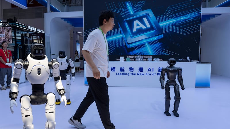 ARCHIVO - Un trabajador pasa junto a robots de la empresa china Lens en el China International...