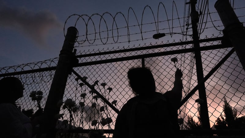 ARCHIVO Varias personas observan las flores en una cerca fuera del Centro de Detención Krome...