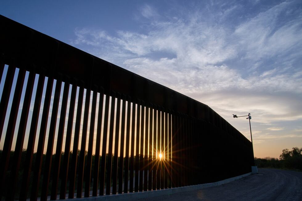 El sol se oculta detrás de un tramo del muro fronterizo, el 18 de junio de 2025, en Mission,...